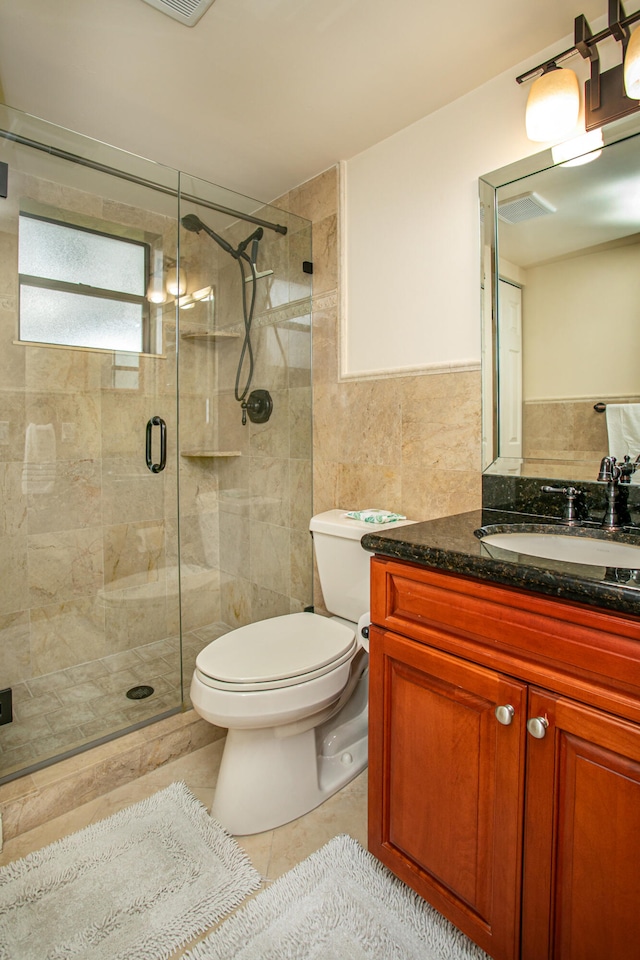 bathroom with toilet, tile patterned floors, walk in shower, tile walls, and vanity