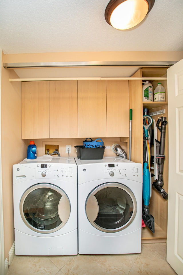 laundry room featuring cabinets, a textured ceiling, and washing machine and clothes dryer