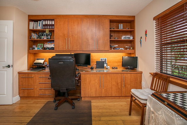 office space with built in desk and light wood-type flooring