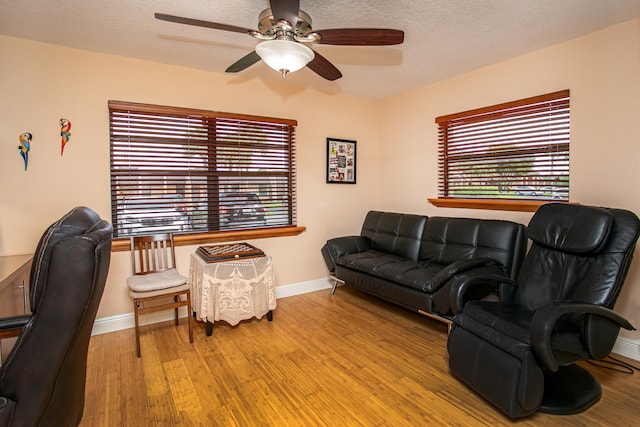 living room with a textured ceiling, light hardwood / wood-style floors, and ceiling fan