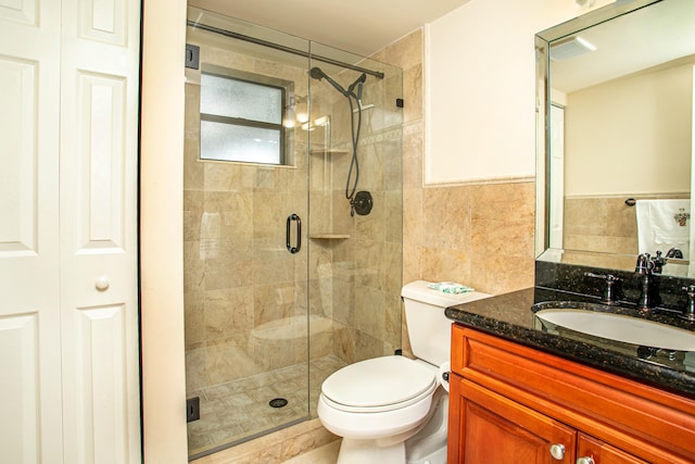 bathroom with vanity, toilet, tile walls, and an enclosed shower