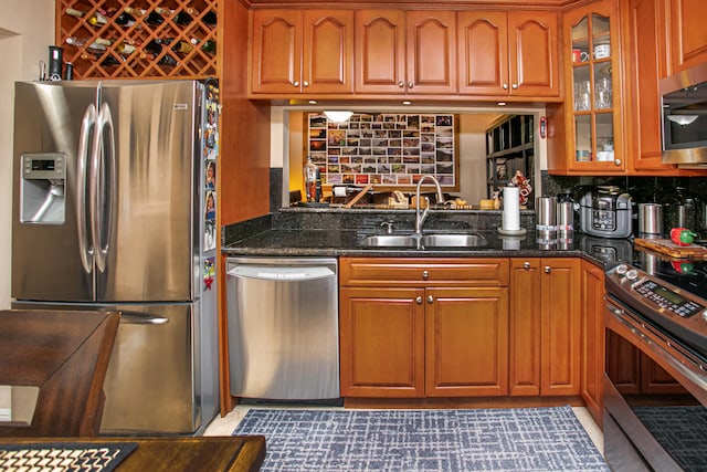 kitchen with sink, appliances with stainless steel finishes, backsplash, and dark stone counters