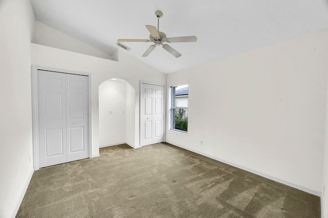 unfurnished bedroom with lofted ceiling, multiple closets, carpet flooring, and ceiling fan