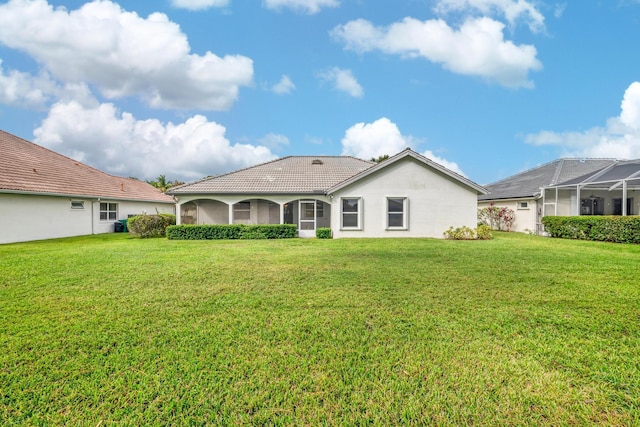 rear view of house featuring a lanai and a lawn