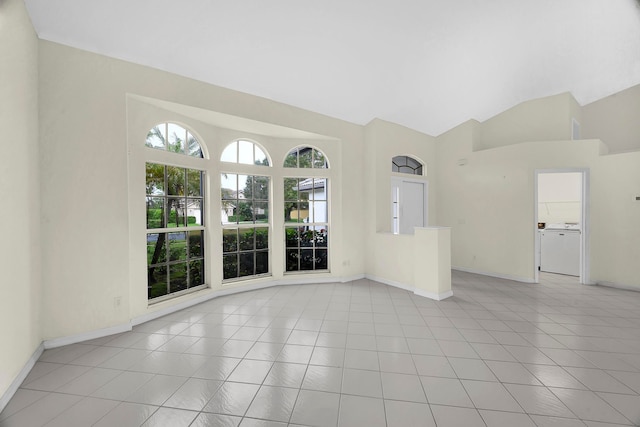 spare room featuring washer / dryer, lofted ceiling, and light tile patterned floors