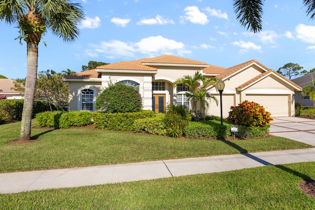 mediterranean / spanish-style house featuring a front yard and a garage