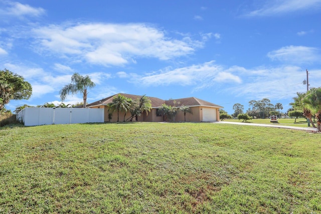 view of yard with a garage, fence, and driveway