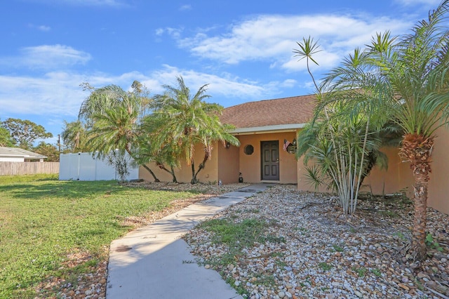 view of front facade featuring fence, stucco siding, and a front lawn