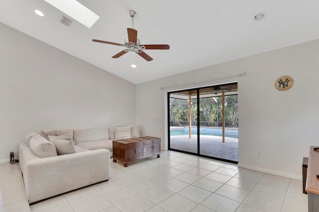 tiled living room with vaulted ceiling with skylight and ceiling fan