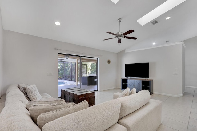 living area featuring visible vents, baseboards, ceiling fan, vaulted ceiling with skylight, and light tile patterned floors