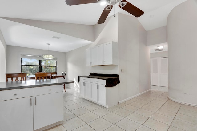 kitchen featuring white cabinetry, light tile patterned floors, and vaulted ceiling