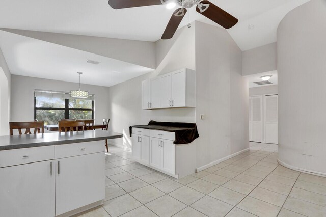 kitchen featuring light tile patterned floors, dark countertops, white cabinets, and a ceiling fan