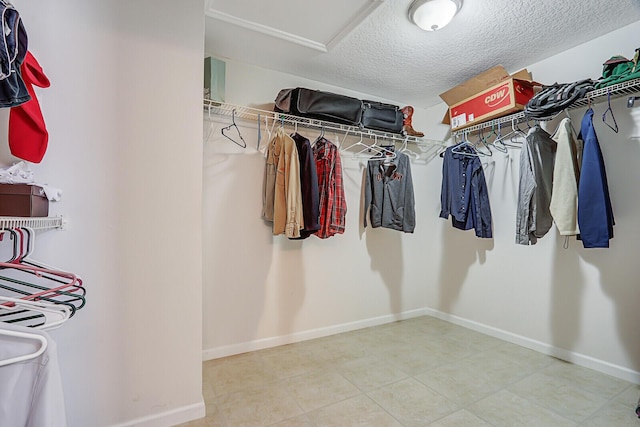 walk in closet featuring attic access and tile patterned floors