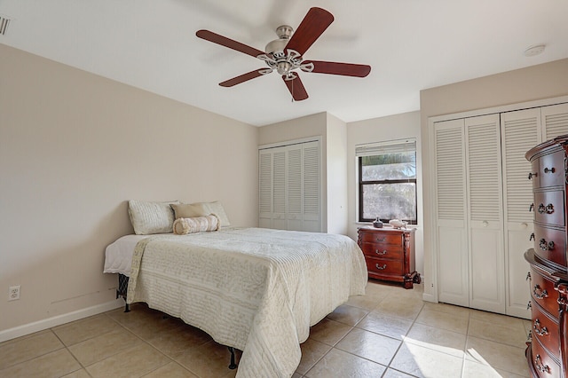 bedroom featuring two closets, light tile patterned flooring, and ceiling fan