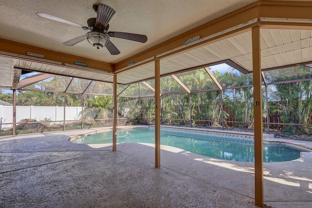 view of swimming pool featuring a patio, glass enclosure, and ceiling fan