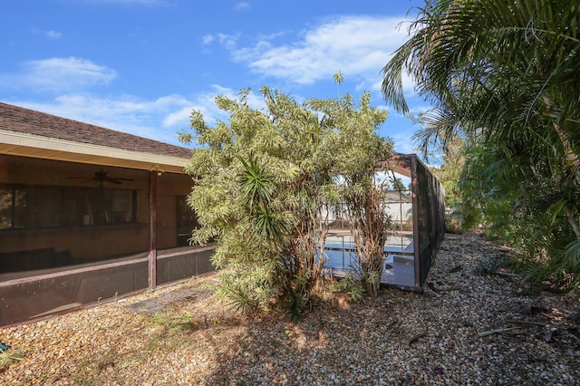 view of side of property featuring a ceiling fan, a lanai, and a pool