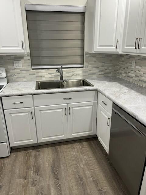 kitchen featuring sink, dark hardwood / wood-style floors, backsplash, stainless steel dishwasher, and white cabinets