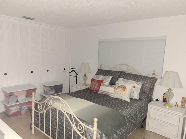 bedroom featuring light tile patterned floors, a textured ceiling, and a closet