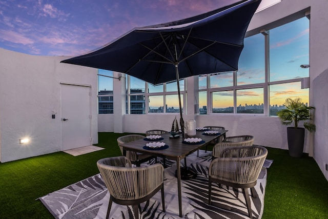 patio terrace at dusk featuring a lawn