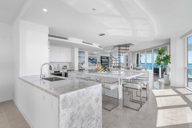 kitchen featuring a kitchen bar, white cabinetry, a healthy amount of sunlight, sink, and kitchen peninsula