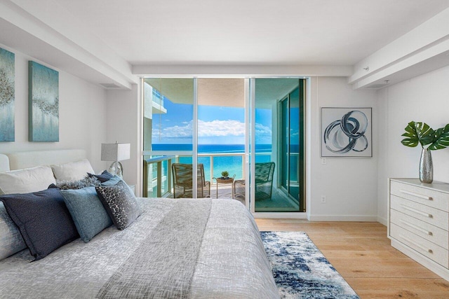 bedroom featuring light hardwood / wood-style flooring, access to outside, and a water view