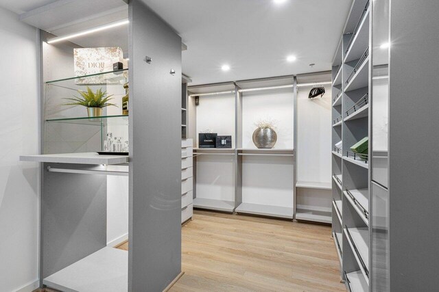 walk in closet with light hardwood / wood-style floors