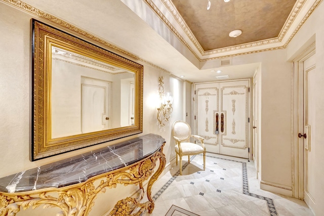 hallway with baseboards, a raised ceiling, visible vents, and crown molding