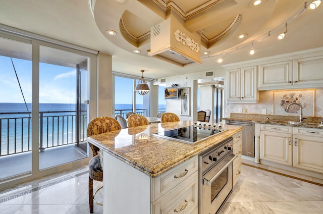 kitchen with a kitchen island, light stone counters, stainless steel appliances, and a sink