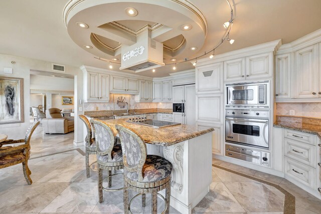 kitchen with built in appliances, a breakfast bar area, stone countertops, backsplash, and a warming drawer