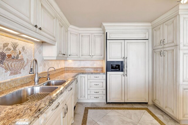 kitchen featuring dark stone counters, built in appliances, cream cabinets, and tasteful backsplash