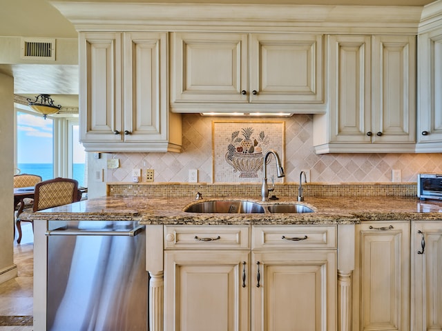 kitchen featuring a water view, stainless steel dishwasher, cream cabinetry, and sink