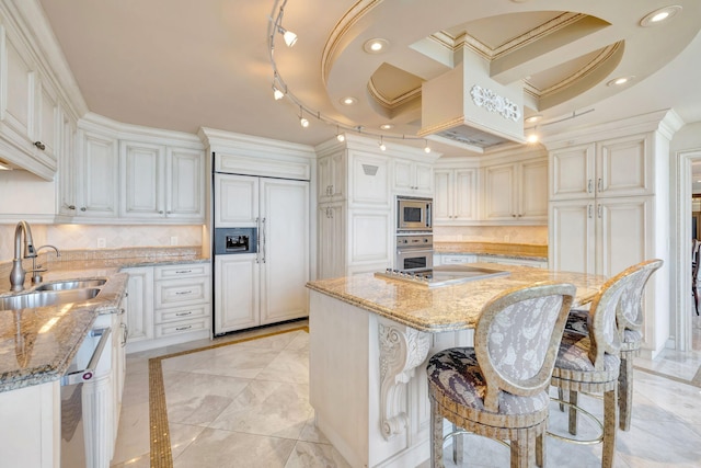 kitchen featuring tasteful backsplash, a kitchen island, built in appliances, light stone countertops, and a sink