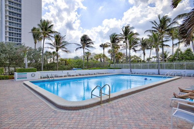 community pool with a patio area and fence