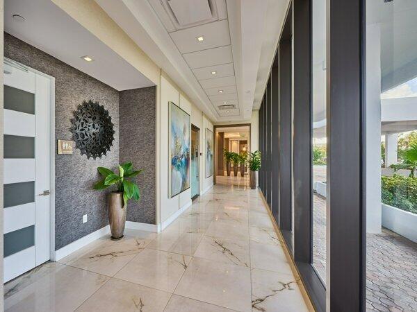 corridor featuring marble finish floor, an accent wall, baseboards, and wallpapered walls