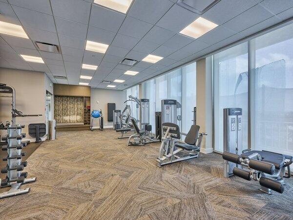 gym with carpet floors, plenty of natural light, visible vents, and a drop ceiling