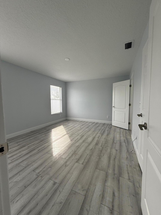 spare room featuring a textured ceiling and light wood-type flooring