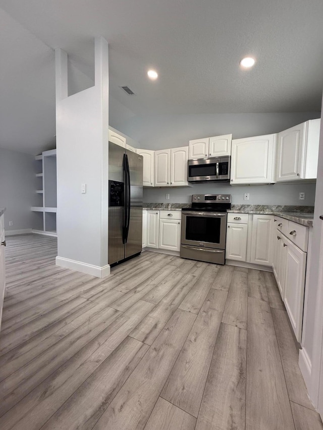 kitchen with white cabinets, stainless steel appliances, light hardwood / wood-style flooring, and lofted ceiling