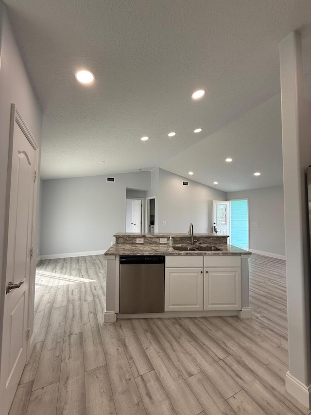 kitchen featuring dishwasher, white cabinets, sink, vaulted ceiling, and light wood-type flooring