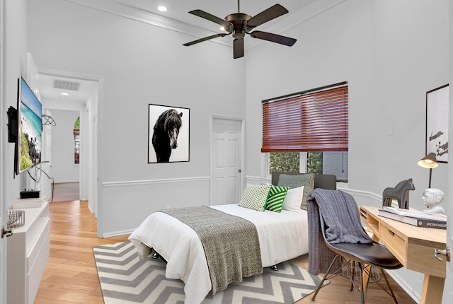 bedroom featuring ceiling fan, a towering ceiling, and light wood-type flooring