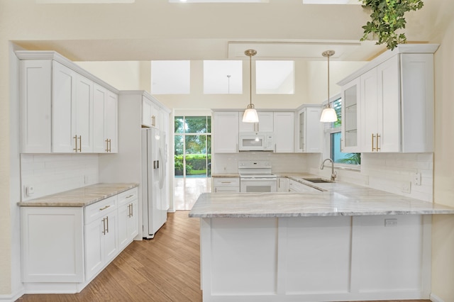 kitchen with kitchen peninsula, sink, pendant lighting, white cabinetry, and white appliances