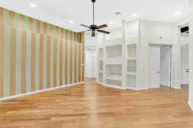 unfurnished living room featuring ceiling fan, light hardwood / wood-style floors, built in features, and a towering ceiling