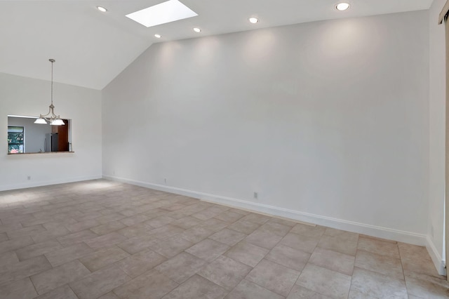 spare room featuring vaulted ceiling with skylight and a chandelier