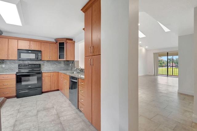 kitchen featuring sink, black appliances, backsplash, and a skylight