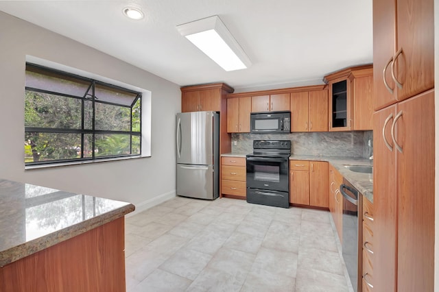 kitchen with decorative backsplash, light stone countertops, and black appliances