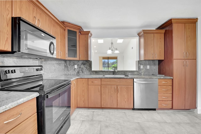 kitchen with backsplash, black appliances, sink, and an inviting chandelier