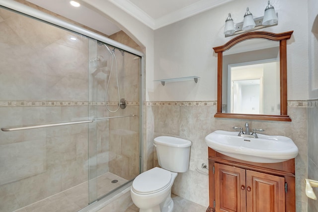 bathroom with toilet, a shower with shower door, vanity, ornamental molding, and tile walls