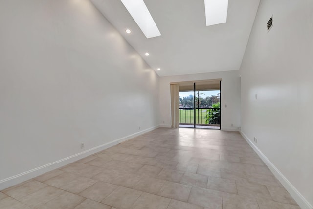 tiled spare room with high vaulted ceiling and a skylight