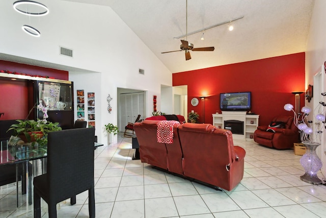 living room with high vaulted ceiling, track lighting, light tile patterned floors, and ceiling fan