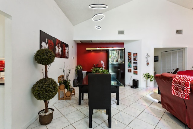 tiled dining room featuring high vaulted ceiling