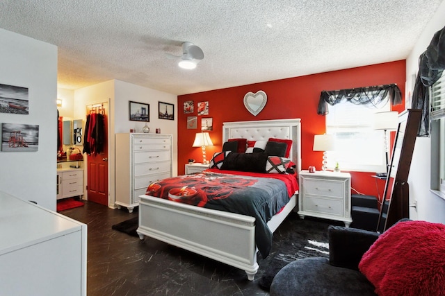 bedroom with a closet, a textured ceiling, ceiling fan, and ensuite bathroom